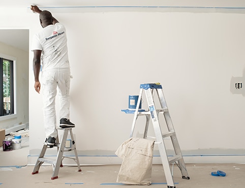 A professional painter uses a step ladder, with a taller ladder on reserve that holds a can of REGAL® Select Interior paint. A professional painter uses a step ladder, with a taller ladder on reserve that holds a can of REGAL® Select Interior paint.